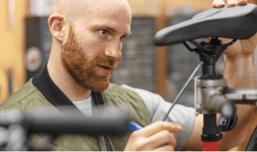 Man fixing a bicycle seat in a workshop